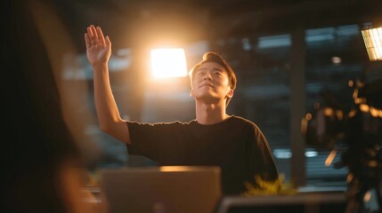 Young Asian man raises hand in creative video production studio setting