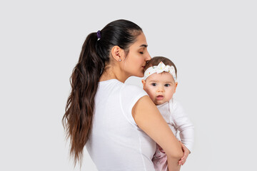 Beautiful young mother kissing her adorable baby on white background.