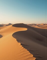 Serene desert landscape with undulating sand dunes under a clear blue sky