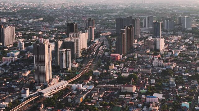 Aerial view of Krung Thon Buri district with high and low rise buildings with skytrain line through at sunset. Bangkok Thailand