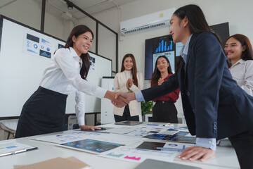 Businesswomen shaking hands after successful meeting in modern office