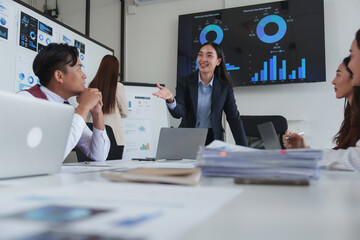 Asian businesswoman leading meeting, explaining charts and business strategy to coworkers
