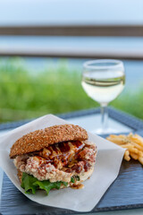 チキンバーガー、フライドポテト、グラスワイン、海が見える眺めがいい飲食店のテラス席