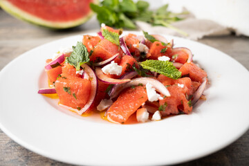Fresh Watermelon Feta Salad with Mint and Red Onion on wooden table
