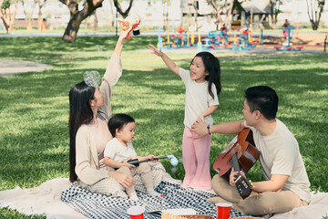 Happy family playing with bubbles during a picnic in the park