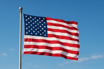 USA flag waving on pole with clear blue sky background. American pride and national symbol concept