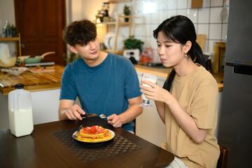 Romantic couple enjoying pancake breakfast together in a cozy kitchen