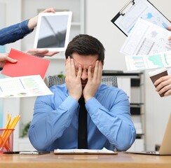 Man overwhelmed by different requests from colleagues at desk in office