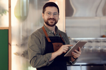 Fototapeta premium Portrait of smiling business owner with tablet in his cafe