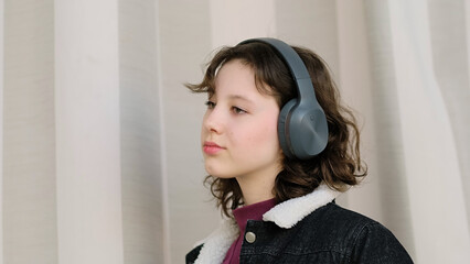 A serene young girl wearing headphones appears to be lost in thought. This image explores the...