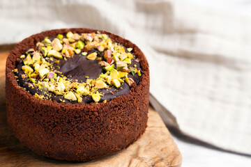 Dubai chocolate cheesecake with crushed pistachio kernels on rustic textured board and cloth napkin