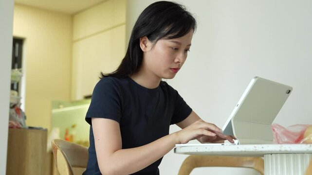 Young Asian woman using tablet for working at home