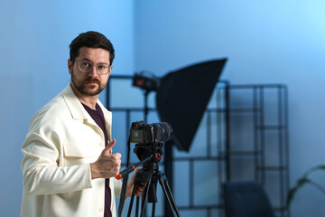 Man with professional video camera in studio, space for text