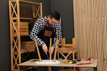 Relaxing hobby. Man assembling stool with screwdriver at table in workshop