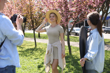 Professional photographers with reflector and camera near model during shooting outdoors on sunny...
