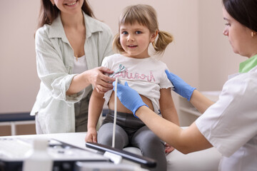Sonographer conducting ultrasound examination of girl's heart. Mother and daughter having...