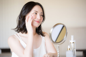 鏡をみる素肌感が美しい若い女性の美容やビューティーイメージクローズアップ　ベージュや黄色背景	
