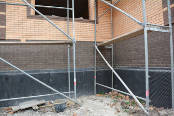 Brick house foundation wall waterproofing in problem corner area.