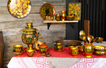 Golden samovar with vibrant khokhloma painting and traditional russian folk painted tableware on table scene depicting russian culture heritage hospitality and tea ceremony concept.