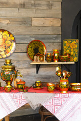 A table is set with traditional russian khokhloma painted teaware including a samovar, cups, and spoons. Russian folk art and culture concept for decoration.