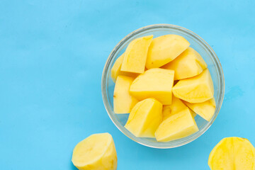 Raw peeled potatoes on blue background