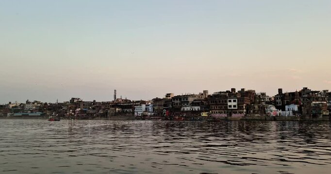 The skyline of Mathura is visible across the Yamuna River, showcasing the city's architectural beauty against the water.