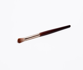 Makeup brush with a light brown bristles, and a metallic gold ferrule, used for blending eyeshadow