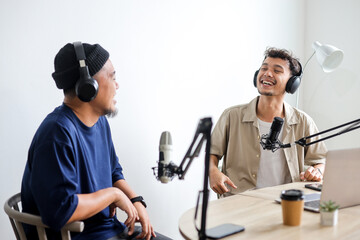 Two Cheerful Radio Host in Headphones Recording Podcast in Broadcasting Studio