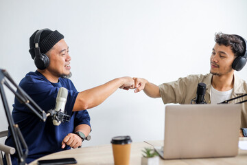 Asian Podcaster Greeting Guest and Doing Fist Bump Gesture While Recording Podcast in Home Studio