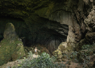 Solo female traveler stand at the entrance to the impressive 'Bat Cave' in traditional Kho Muong village in rural Vietnam
