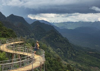 Solo male traveler enjoys the scenic view of a picturesque valley and forested mountain peaks from Hang Kia village in northern Vietnam