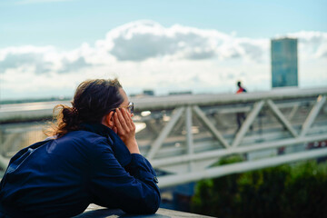 Person in blue jacket looking out over cityscape with clouds and a distant skyscraper. Brussels, Belgium