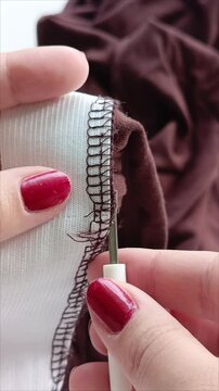 The woman opens the seam of the fabric. The rasper opens the seam of the elastic band. 