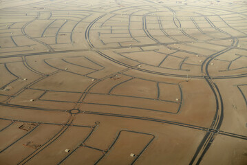 Aerial view of desert land divided into marked plots for development, with intersecting roads. Abu Dhabi, UAE