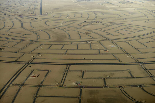 Aerial view of a vast desert area with winding roads and infrastructure under construction. Abu Dhabi, UAE