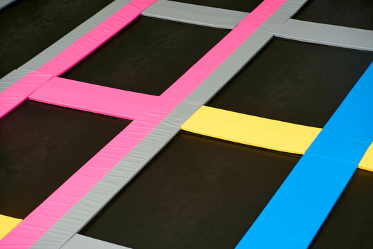 Colorful trampoline grid with pink, yellow, gray, and blue stripes on a dark surface. Abu Dhabi, UAE