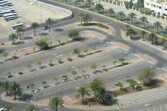 Aerial view of an empty parking lot with scattered palm trees and surrounding roads. Abu Dhabi, UAE