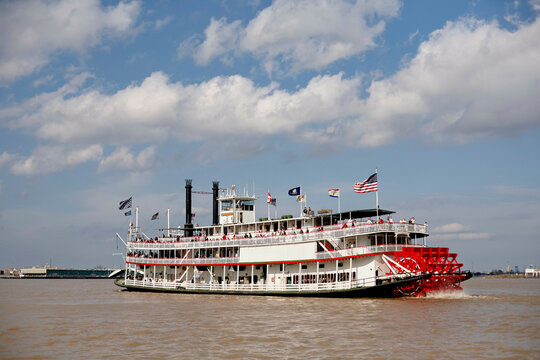Paddle steamboat cruising on a river under a partly cloudy sky. Road Trip USA