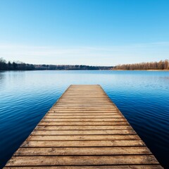 Obraz premium Serene lake view from a wooden dock under a clear blue sky.