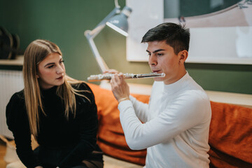 A young student learns to play flute under the guidance of a music teacher indoors.