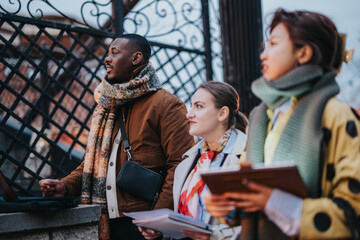 A diverse group of three individuals gathered outside, engaged in meaningful conversation while holding documents, exemplifying teamwork and collaboration in a professional sphere.