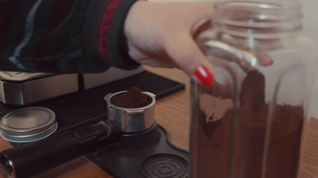 A barista locks a stainless-steel portafilter filled with freshly ground espresso into a dosing collar mounted on a wooden countertop. The dosing station provides precise tamp alignment and excess