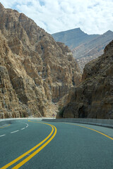 Lonely road winding through rugged mountain landscape. Mountain road, drive, route - ideal for travel, adventure, and driving freedom
