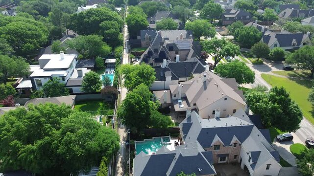 Solar roof panels on multimillion dollar homes with swimming pools, luxury amenities in affluent Preston Hollow neighborhood, Dallas, treed lined street back alley, overhead electric service drop