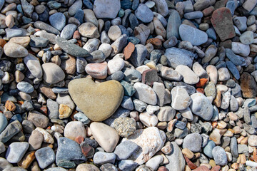 a beautiful, large, weighted stone as a heart shape between the many colorful pebbles on the beach in Kemer Turkey