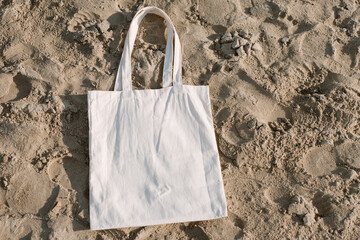 White cotton or mesh bag on beach sand background. Zero waste, no plastic, eco friendly shopping,...