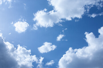 Fototapeta premium Blue sky. Sunlight. White cumulus clouds against the blue sky. White clouds. Copy space. Cloudy landscape. Natural background. Sunny day. Background of fluffy clouds on a warm sunny day