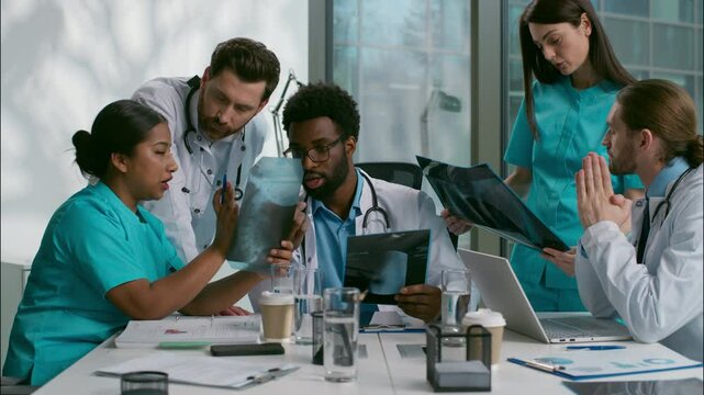 Multiethnic doctors medical diagnostic team meeting heath research xray analyzing African men Indian Caucasian women diverse nurse surgeon medicare five people talk discuss checkup results at clinic