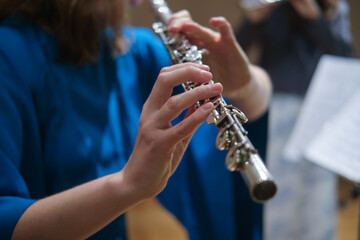 Close-up of person playing silver flute in indoor setting. Studio music photography. Classical music and musical performance concept. Close-up shot