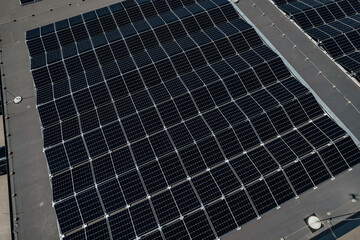 Overhead shot of a large-scale solar panel array on a flat rooftop, organized in neat rows for...